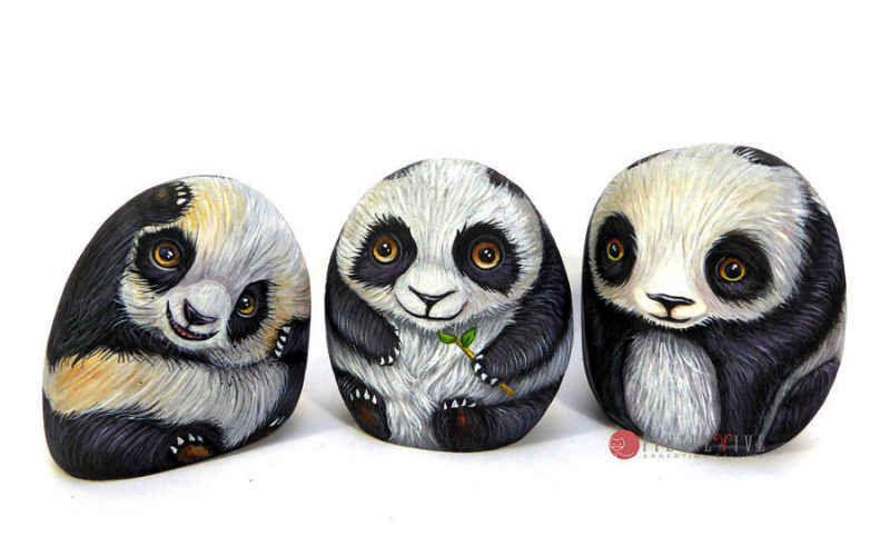 Tre cuccioli di panda dipinti su ciottoli